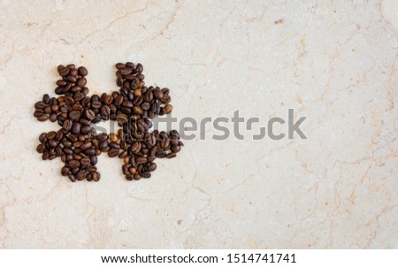 Hash tag icon symbol made from roasted coffee beans on marble surface flat lay image with copy space for text - modern social media icons and symbols.