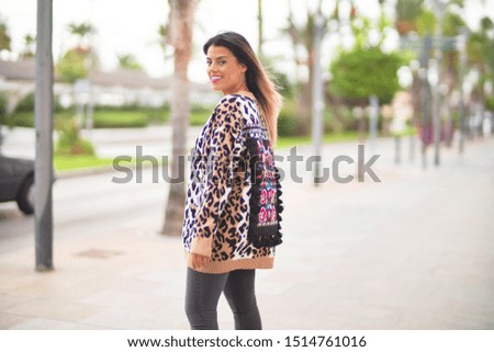 Young beautiful girl wearing animal print cardigan walking at the town street