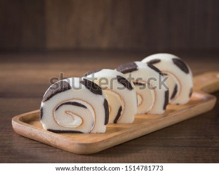Milk cake roll striped milk cow with soft cream inside on wood dish and wood background selective focus and copy space