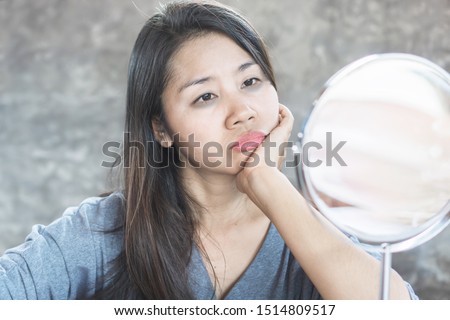 unhappy Asian woman age 40 checking her dark eyes circle problem in mirror 