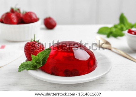 Delicious fresh red jelly with berries and mint on white wooden table