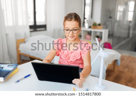 children, education and technology concept - student girl using tablet computer at home