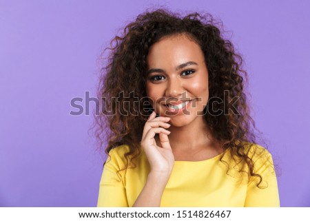 Image of gorgeous african american woman having curly hair posing at camera with smile isolated over violet background