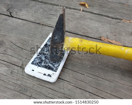 smashing a smartphone screen with a hammer, recycling old electronics