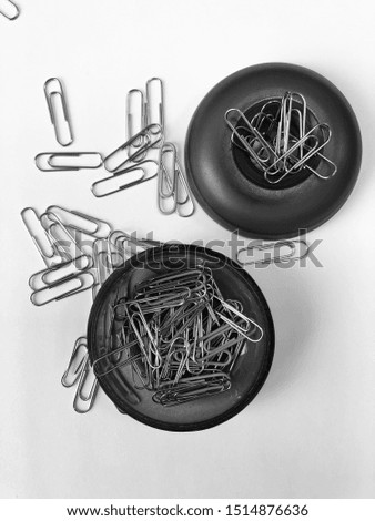 Metal paper clips on black magnetic coasters on white background