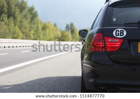 Estate vehicle parked up on a autostrada/highway/motorway showing the road disappearing. The car has a GB country of origin sticker, with the background in blur. showing the car in focus. Royalty-Free Stock Photo #1514877770