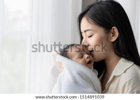 Portrait of asian young mother kissing her cute newborn baby in white bed room. Wife and mother's day concept. Royalty-Free Stock Photo #1514891039