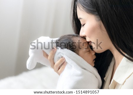 Close up asian young mother kissing her cute newborn baby. Wife and mother's day concept.