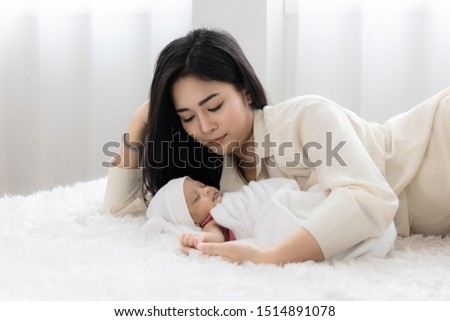 Asian young mother with cute newborn baby sleeping in bed. mother 's day concept.