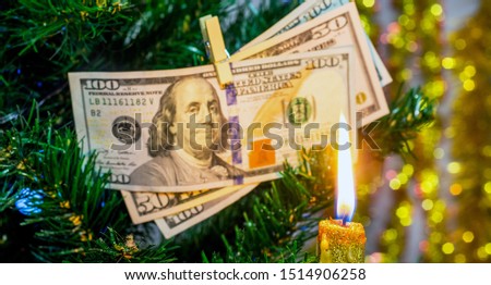 Christmas candle on the background of a Christmas tree decorated with dollars