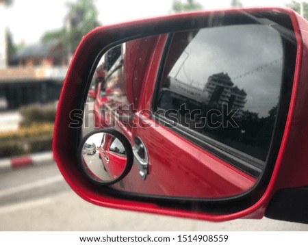 Left-wing mirror with a blurred picture inside a red car. Reflecting on a rearview mirror image.