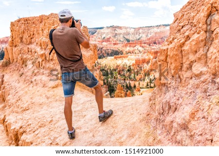Man tourist person standing taking picture of view with camera at Queens Garden Navajo Loop trail at Bryce Canyon National Park in Utah