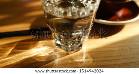 transparent glass glass with water leaves glare on a wooden table. abstraction. ripples