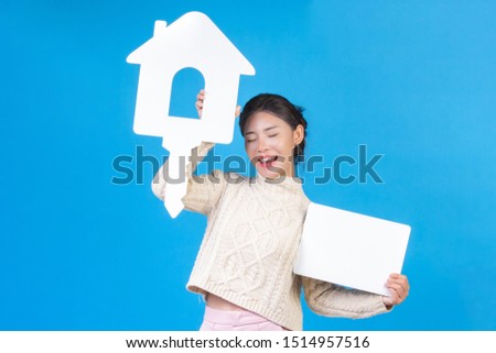 A beautiful woman wearing a new shirt, a long-sleeved white carpet with the house symbol and a white sign on a blue background. Trading concept.