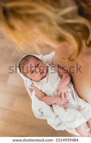 Newborn in arms looks at his mother.