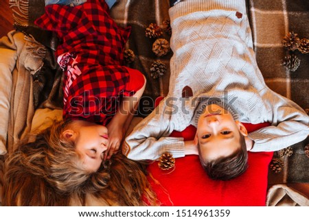 Cute little sister with long hair and an older brother in autumn scenery with pumpkins and plaids play in the studio
