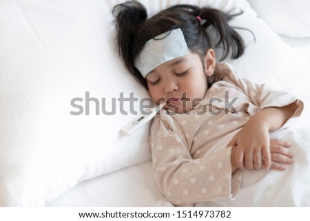 Medical check up and treatment concept. Mother is measure the temperature of little Asian kid girl. Sick child with fever and illness in bed. Royalty-Free Stock Photo #1514973782