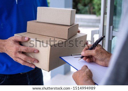 The shopper girl signs on the clipboard to receive the package box from the delivery man. Fast delivery service