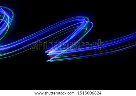 Long exposure photograph of neon multi  colour in an abstract swirl, parallel lines pattern against a black background. Light painting photography.