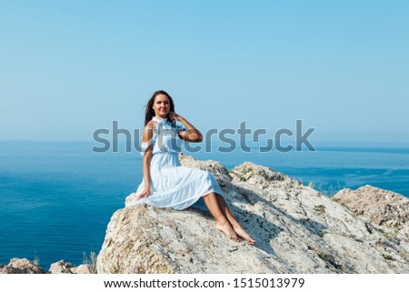 woman in dress looks at the ocean view from the cliff