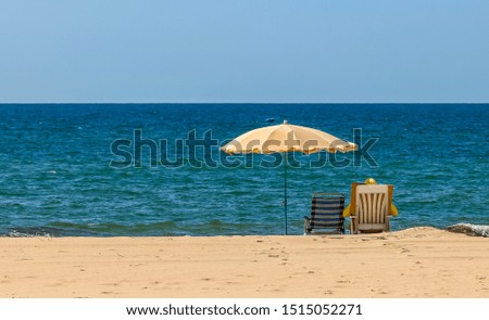 Isolated at beach. Beach umbrella and beach chair, yellow on the beach in front of the sea. Summer activity, isolated and social distance on summer.