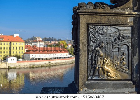 Metal engraving of a warrior with a dog with an old building on the background and the river.
