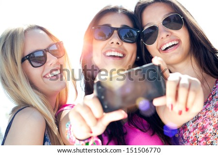 Outdoor portrait of three friends taking photos with a smartphone Royalty-Free Stock Photo #151506770