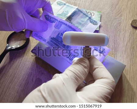 Verification of banknotes by an ultraviolet lamp for authenticity.