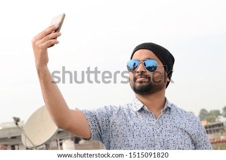 Young Indian man taking selfie on the roof of the building in winter season