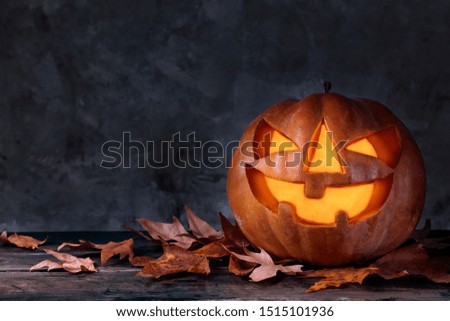 Orange pumpkin carved into creepy and funny Jack o Lantern w/ glowing eyes on dark background. All hallows night. Copy space, close up, top view. Halloween party decoration. Trick or treat concept.