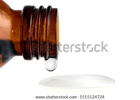 Amber medical bottle with spilled liquid on a white isolated background. Brown glass bottle with liquid close-up