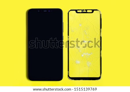 Cell phone and broken safety glass on a yellow background. Close-up.