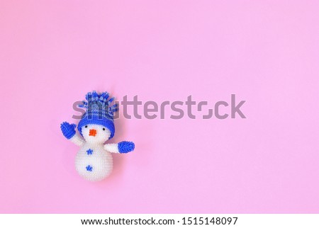 Christmas picture of snowman toy on the pink background in minimalist style top view. Snow figure as a symbol of new year and winter holidays card picture. Flat lay background.