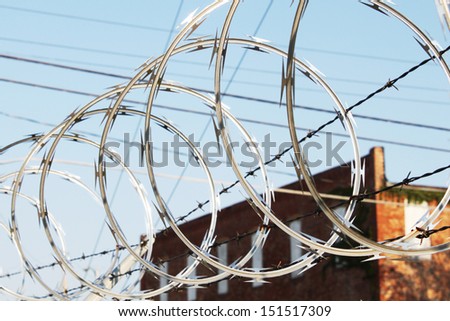 Razor wire and barbwire tangled over a chain link fence