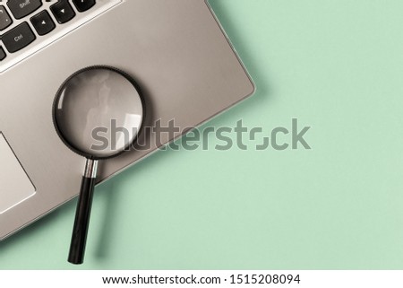 Concept information search. Laptop computer with magnifying glass on mint background. Searching information data on internet. Top view. Flat lay. Neo mint color