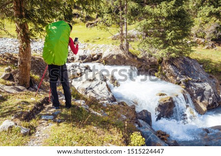 Man photographing a small waterfall on a mountain river