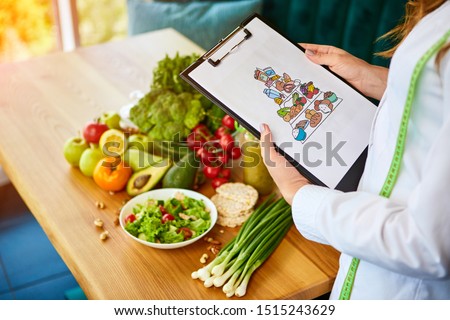 Holding schematic meal plan for diet with various healthy products on the background. Weight loss and right nutrition concept. Eating food pyramid Royalty-Free Stock Photo #1515243629