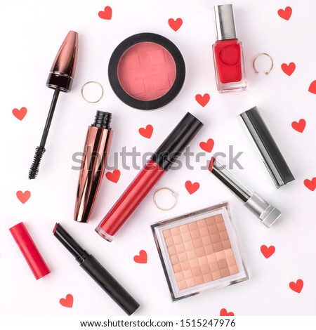 Flat lay composition top view photography of make up and feminine women accessories in a set on a dressing table or desk with valentines style red hearts. Blush, mascara, nail polish lipstick lipgloss