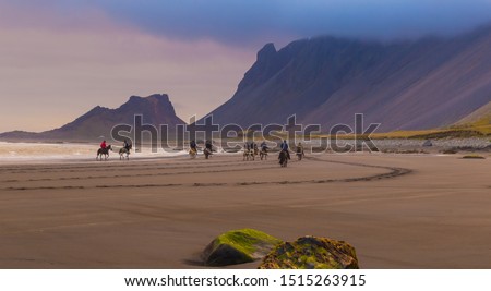 Fantastic summer day on the Stokksnes headland. Group of tourists riding horses along the ocean at low tide. Vestrahorn (Batman) mountain on background. Southeastern Iceland, Europe. Visit Iceland.
