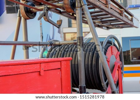 Vintage fire and rescue equipment. A fragment of aged  equipment (rolled fire hoses and wooden fire ladder) closeup on a  red  fire truck 