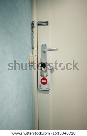 Modern hotel room door with do not disturb warning sign on door knob