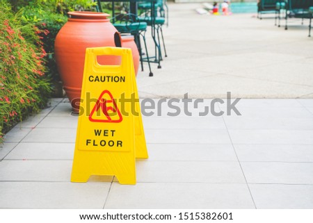yellow caution wet floor sign board on floor near swimming pool