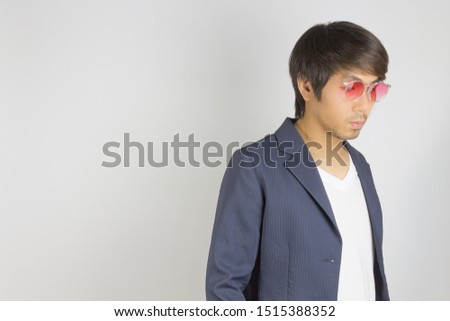 Portrait Asian Casual Businessman in Navy Blue Suit Wear Red Eyeglasses at Right Frame on Grey Background. Casual businessman wear suit fashion in semi formal style