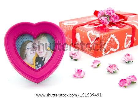heart photo frame with smiling couple and present with pink roses on the background