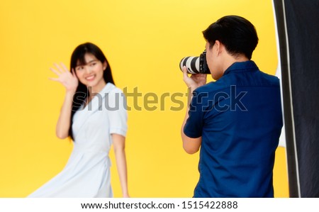 Behind the scenes, photographers are using cameras and lenses to shooting pictures of beautiful young women models smiling and posing in the studio with the backdrop and studio lights. Selective focus