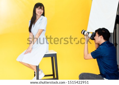 Behind the scenes, photographers are using cameras and lenses to shooting pictures of beautiful young women models smiling and posing in the studio with the backdrop and studio lights. Selective focus