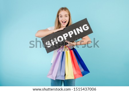 happy young beautiful girl with shopping sign and colorful shopping bags isolated over blue