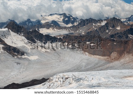 Caucasus mountains near Elbrus volcano with glaciers, clouds and peaks.