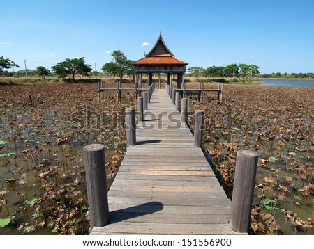 Thai house with wooden bridge in lotus pool