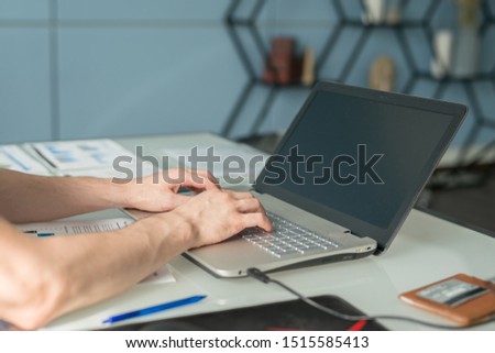 young man working with laptop, view of hands on notebook , business person at workplace.